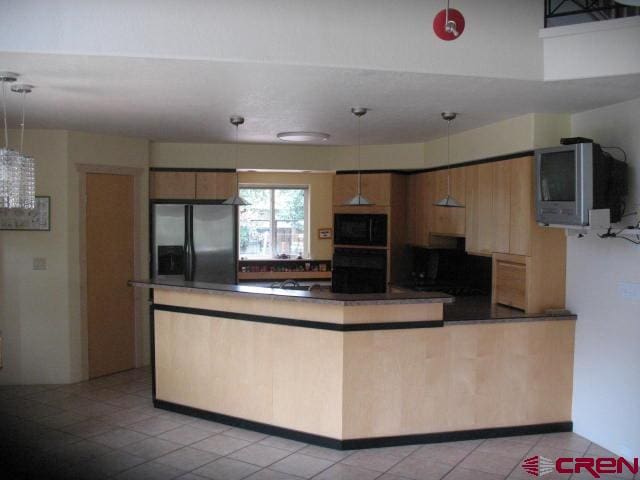 kitchen with black appliances, hanging light fixtures, and light tile floors