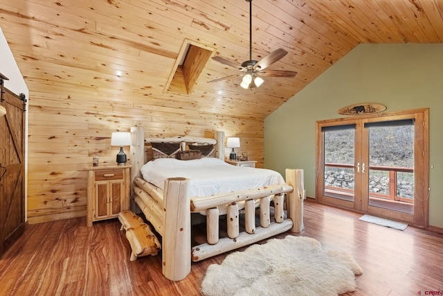 bedroom featuring ceiling fan, wood ceiling, wood-type flooring, a barn door, and wooden walls