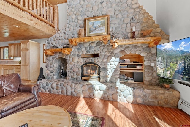 living room featuring a baseboard heating unit, a high ceiling, a fireplace, and hardwood / wood-style floors