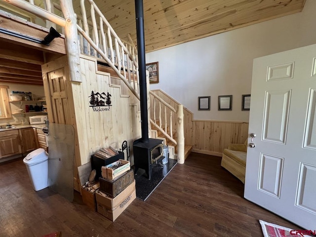 interior space featuring lofted ceiling, wood walls, wood ceiling, a wood stove, and hardwood / wood-style floors