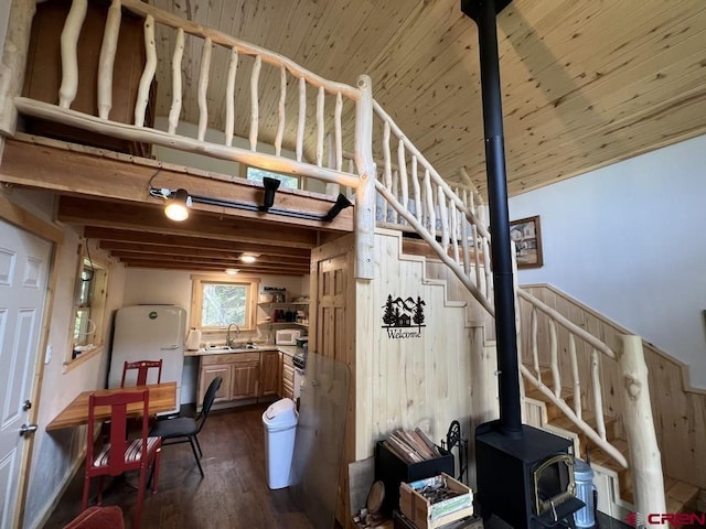 staircase with wood-type flooring, a wood stove, sink, wooden ceiling, and beam ceiling