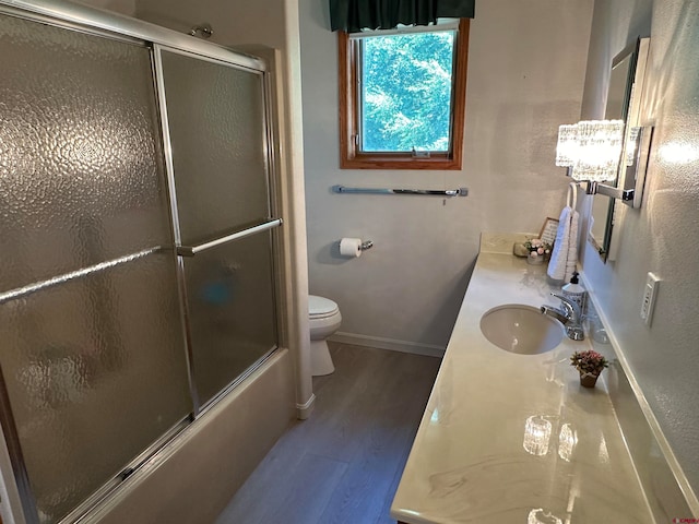 full bathroom featuring vanity, hardwood / wood-style flooring, shower / bath combination with glass door, and toilet