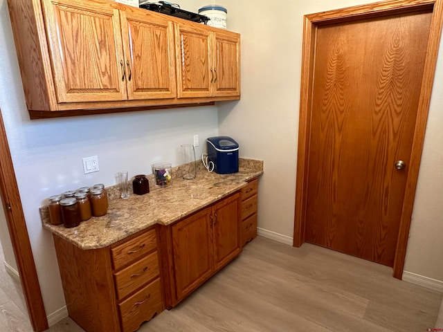 bar featuring light stone counters and light hardwood / wood-style floors