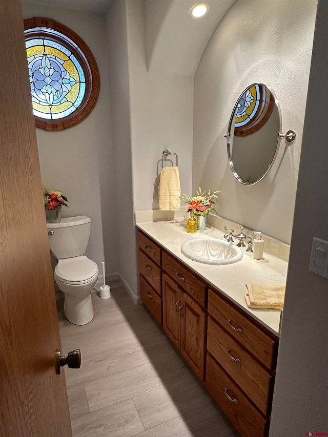 bathroom with wood-type flooring, toilet, and vanity