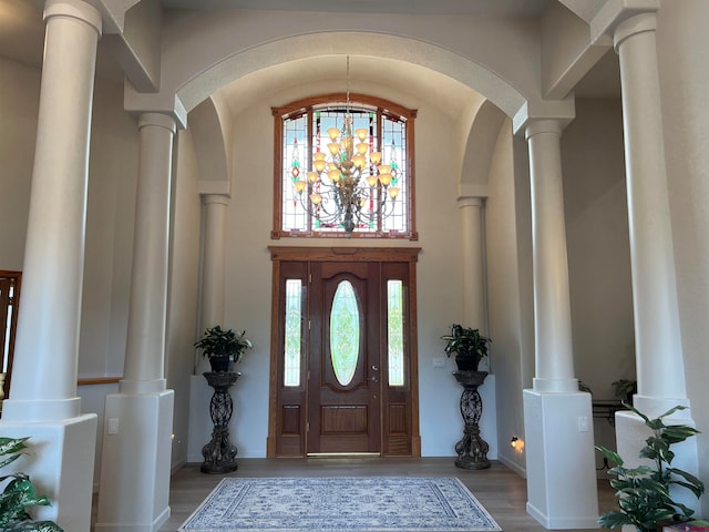 foyer entrance featuring ornate columns, lofted ceiling, and hardwood / wood-style flooring