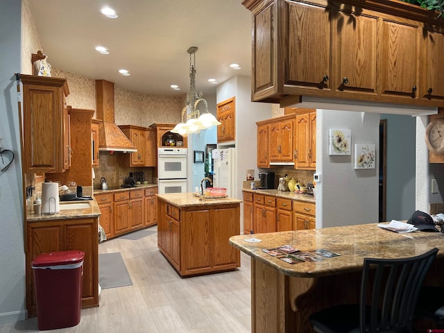 kitchen with decorative backsplash, light hardwood / wood-style flooring, a center island with sink, and custom range hood