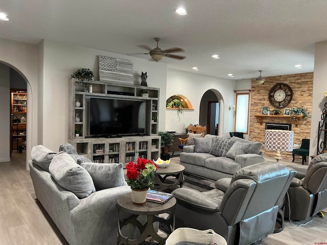 living room featuring a textured ceiling, ceiling fan, and light hardwood / wood-style floors