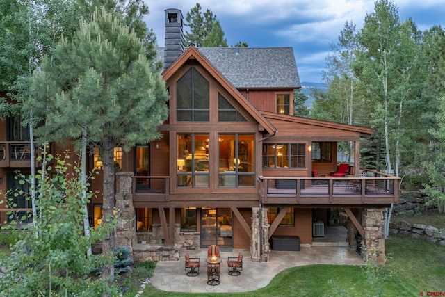 rear view of house with a patio, a yard, a deck, and a fire pit