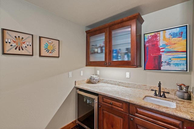 bar with wine cooler, light stone countertops, and sink