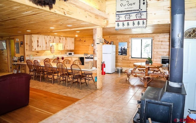 tiled dining area with wood walls, a wood stove, and electric panel