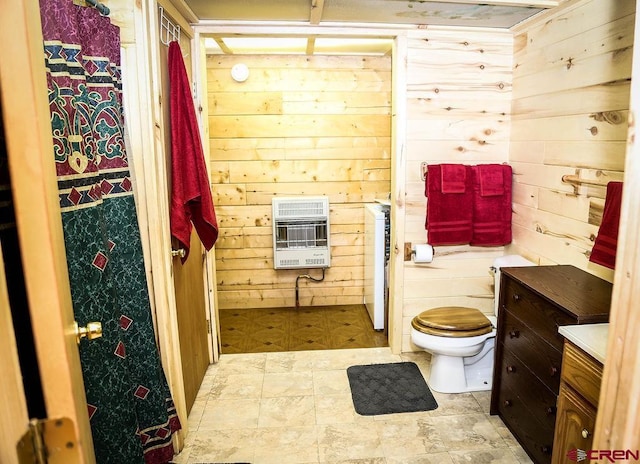 bathroom with heating unit, vanity, tile patterned floors, wooden walls, and toilet