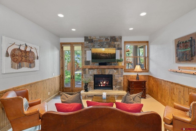 carpeted living room with plenty of natural light, a fireplace, french doors, and wood walls