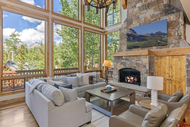 living room with a fireplace, a towering ceiling, and light hardwood / wood-style flooring