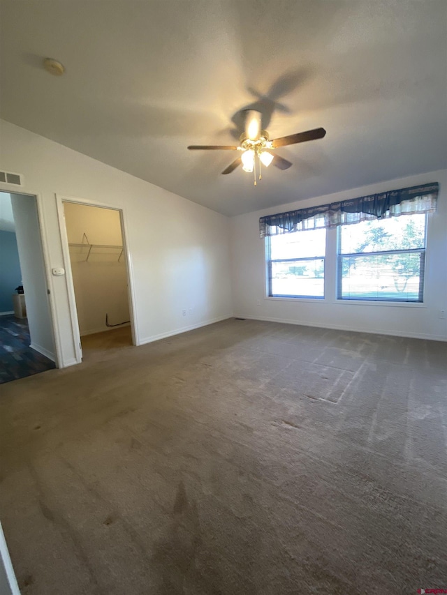 interior space with dark colored carpet, lofted ceiling, and ceiling fan