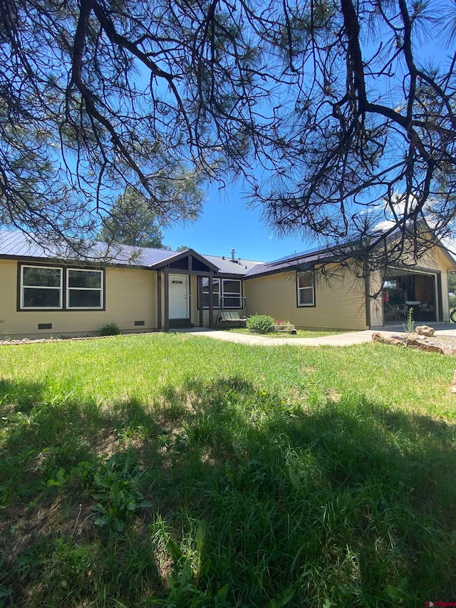 rear view of house featuring a garage and a lawn