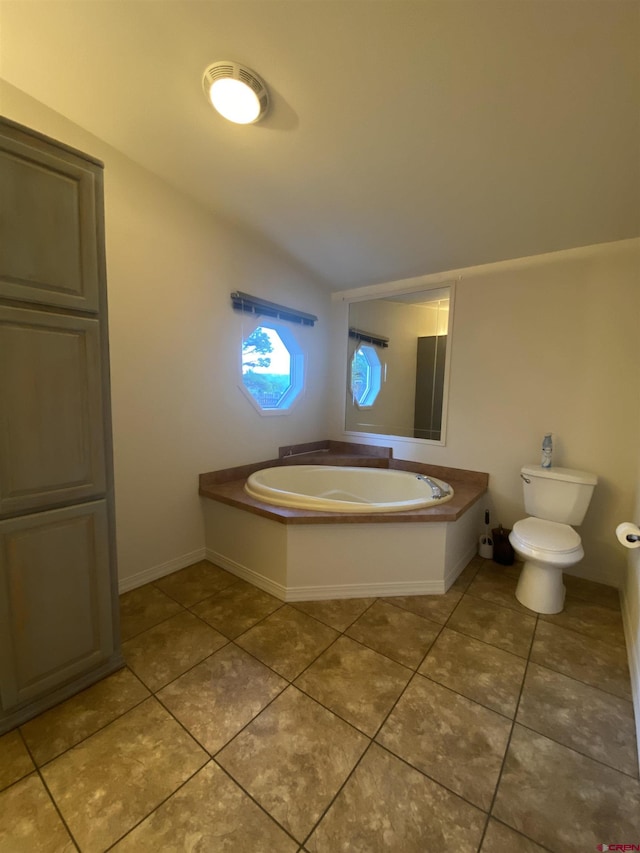 bathroom featuring lofted ceiling, a tub, tile patterned floors, and toilet