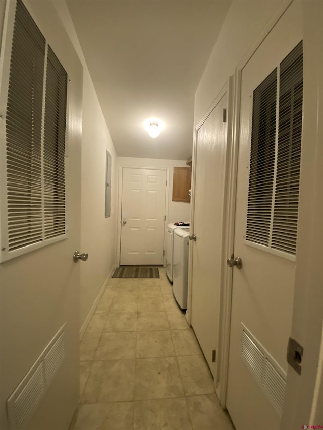 hallway featuring washing machine and dryer, light tile patterned flooring, and electric panel