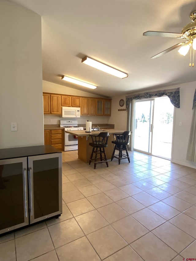 kitchen featuring light tile patterned flooring, white appliances, lofted ceiling, and a breakfast bar