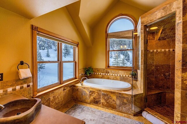 bathroom with tile patterned flooring, shower with separate bathtub, and vaulted ceiling