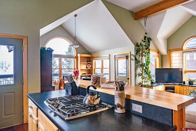 kitchen with beam ceiling, pendant lighting, stainless steel gas stovetop, and high vaulted ceiling