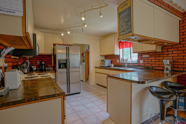 kitchen with stainless steel appliances, sink, kitchen peninsula, backsplash, and track lighting