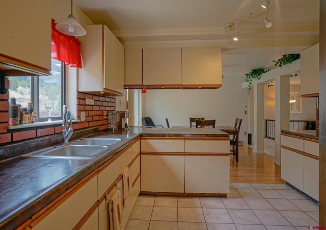 kitchen featuring decorative backsplash, rail lighting, sink, light hardwood / wood-style floors, and kitchen peninsula