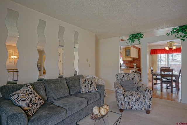 living room featuring carpet floors, a textured ceiling, and ceiling fan with notable chandelier