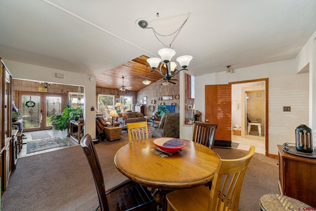 dining area featuring french doors, ceiling fan with notable chandelier, carpet flooring, and vaulted ceiling