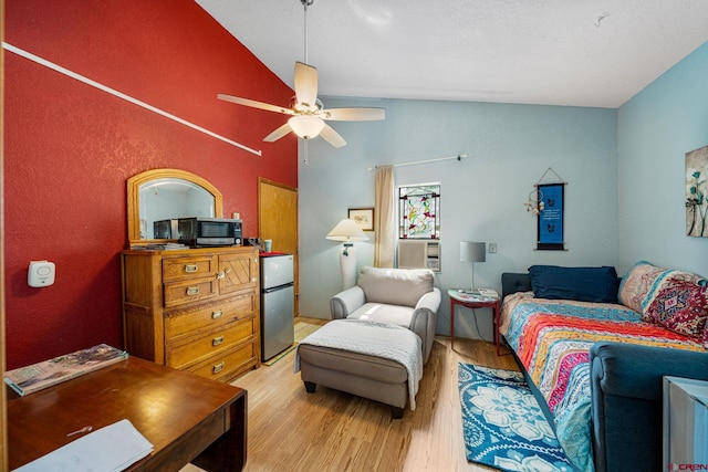 bedroom with light hardwood / wood-style floors, stainless steel refrigerator, lofted ceiling, and ceiling fan