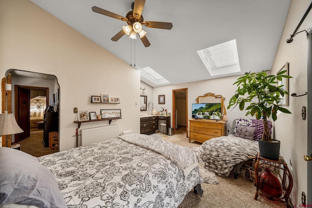 carpeted bedroom with ensuite bath, lofted ceiling with skylight, and ceiling fan