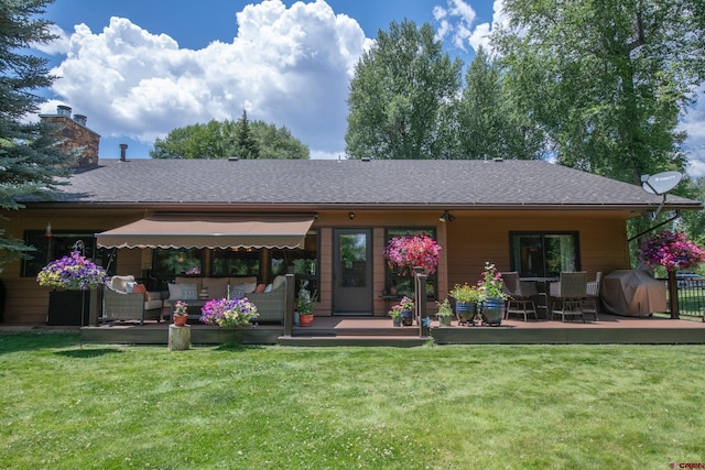 back of house with outdoor lounge area, a lawn, a shingled roof, and a chimney