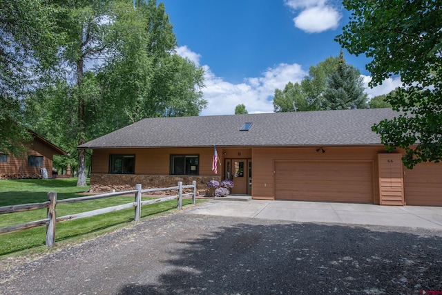 ranch-style home with a fenced front yard, stone siding, roof with shingles, and an attached garage