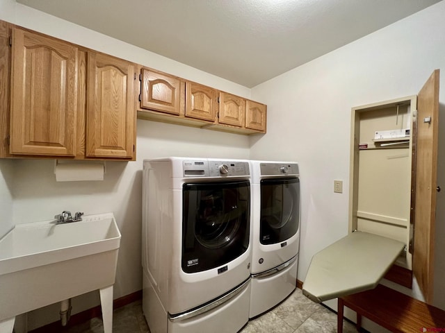 laundry area with a sink, cabinet space, baseboards, and washer and clothes dryer