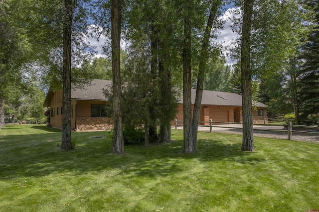 view of front of house featuring a front yard, fence, an attached garage, concrete driveway, and stone siding