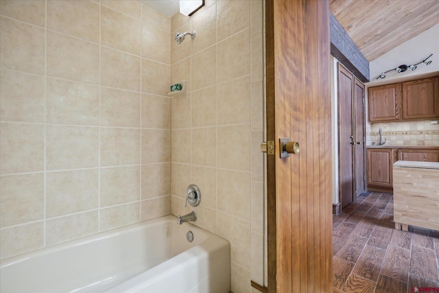 bathroom with vaulted ceiling, tile walls, tiled shower / bath combo, and hardwood / wood-style floors