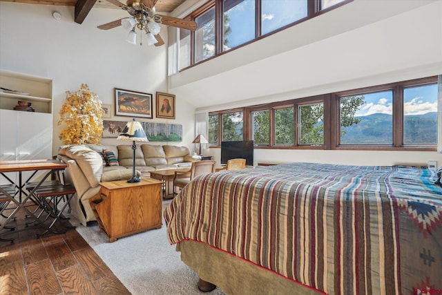 bedroom featuring beam ceiling, a high ceiling, hardwood / wood-style floors, and ceiling fan