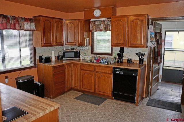 kitchen featuring sink, dishwasher, light tile patterned floors, and plenty of natural light