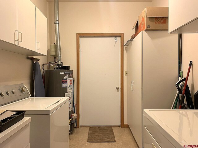 laundry room featuring washing machine and clothes dryer, gas water heater, and cabinets