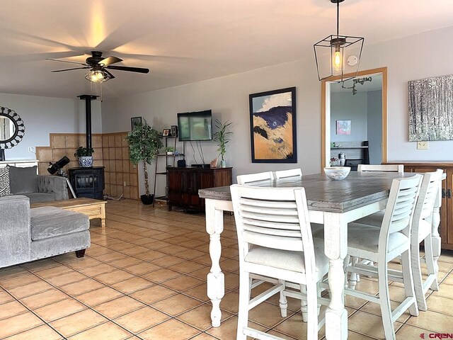 tiled dining room with a wood stove and ceiling fan