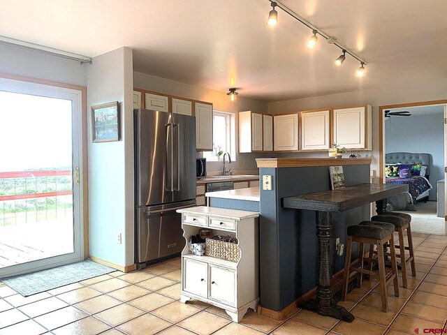 kitchen with stainless steel fridge, a center island, light tile patterned floors, and plenty of natural light