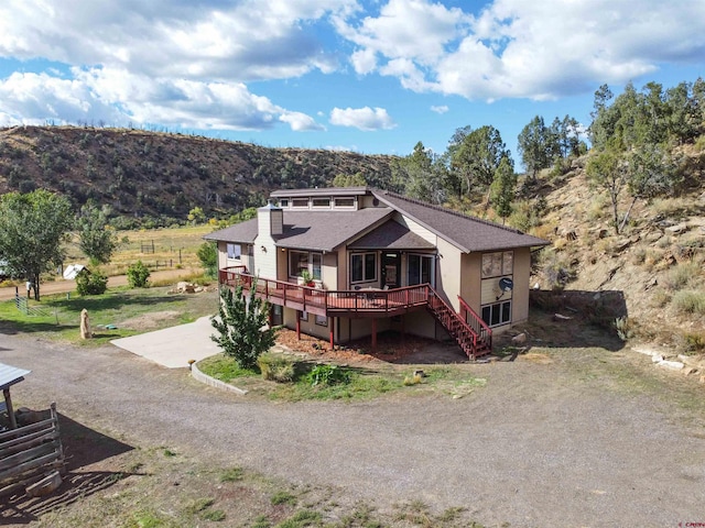 view of front of house featuring driveway, a deck with mountain view, and stairs