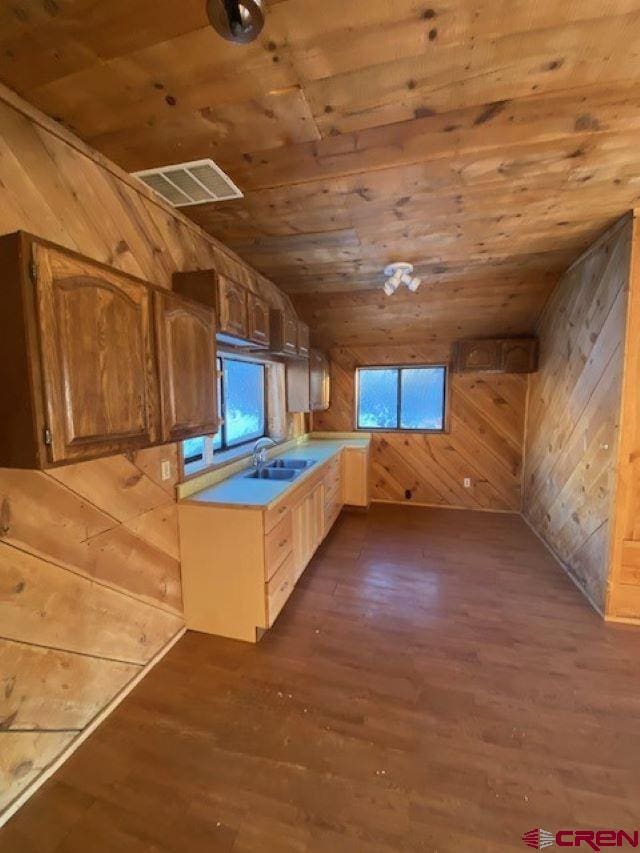 kitchen featuring wooden walls, a sink, visible vents, wood ceiling, and light countertops