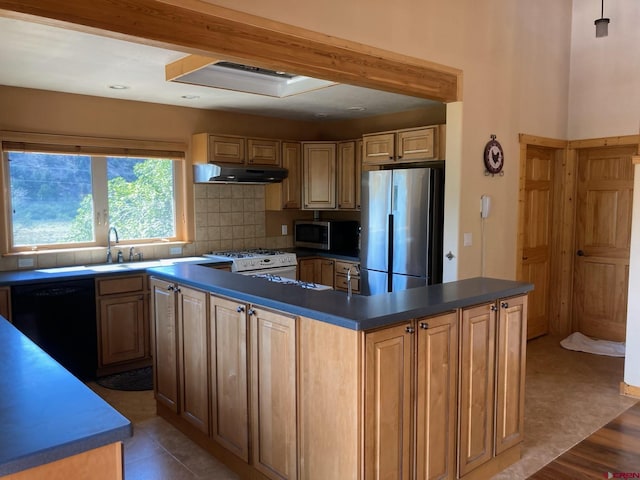 kitchen featuring a center island, dark countertops, appliances with stainless steel finishes, a sink, and under cabinet range hood