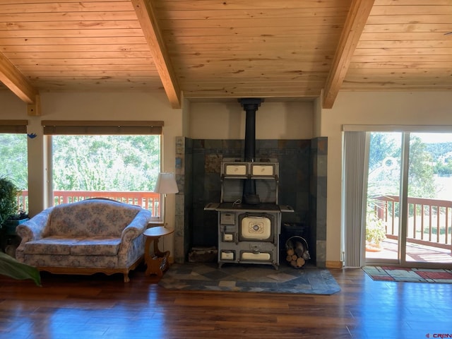 living room with a wood stove, dark wood-type flooring, and beamed ceiling