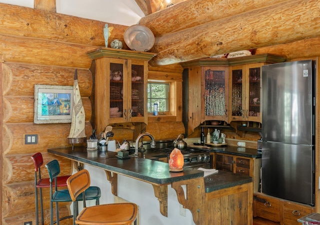 kitchen with a breakfast bar area, stainless steel refrigerator, kitchen peninsula, black range oven, and log walls