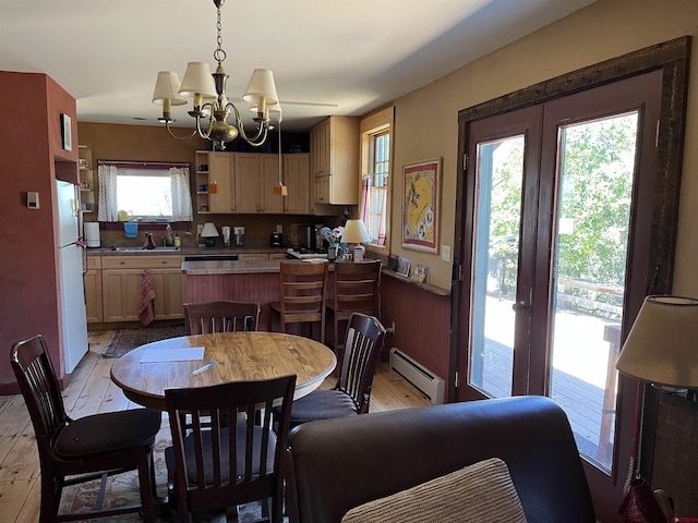 dining area with a baseboard radiator, a healthy amount of sunlight, an inviting chandelier, and light wood-type flooring