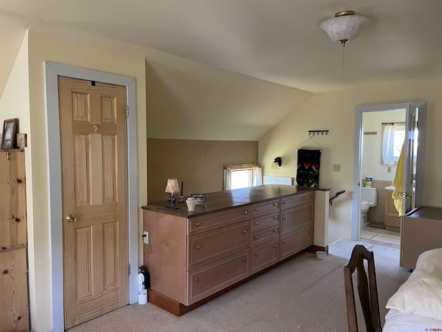 bedroom with light carpet, vaulted ceiling, and ensuite bathroom