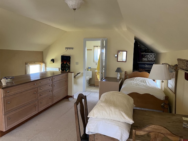 bedroom featuring lofted ceiling, ensuite bathroom, and light colored carpet