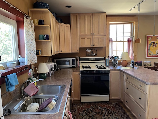 kitchen featuring light brown cabinetry, range with gas stovetop, sink, and a wealth of natural light