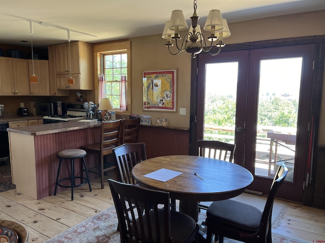 dining room featuring french doors, a notable chandelier, and light hardwood / wood-style flooring